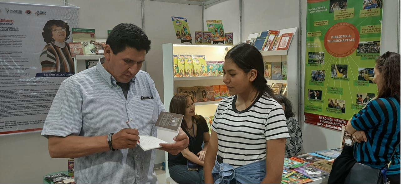 David Vildoso firmando libros para una joven lectora en la Feria del Libro