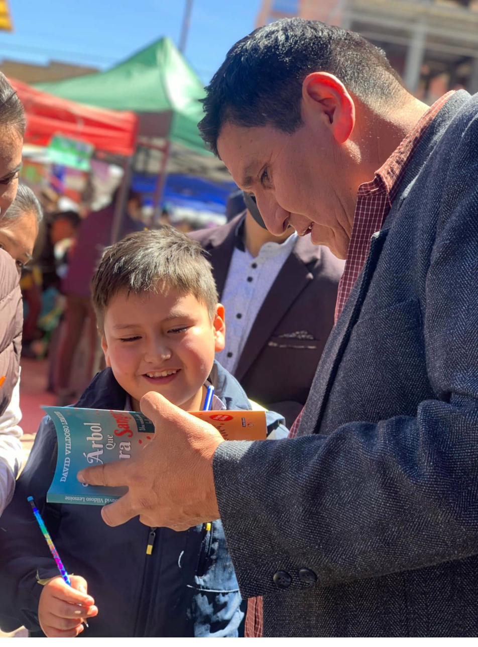 David Vildoso firmando un libro para un niño en una feria al aire libre